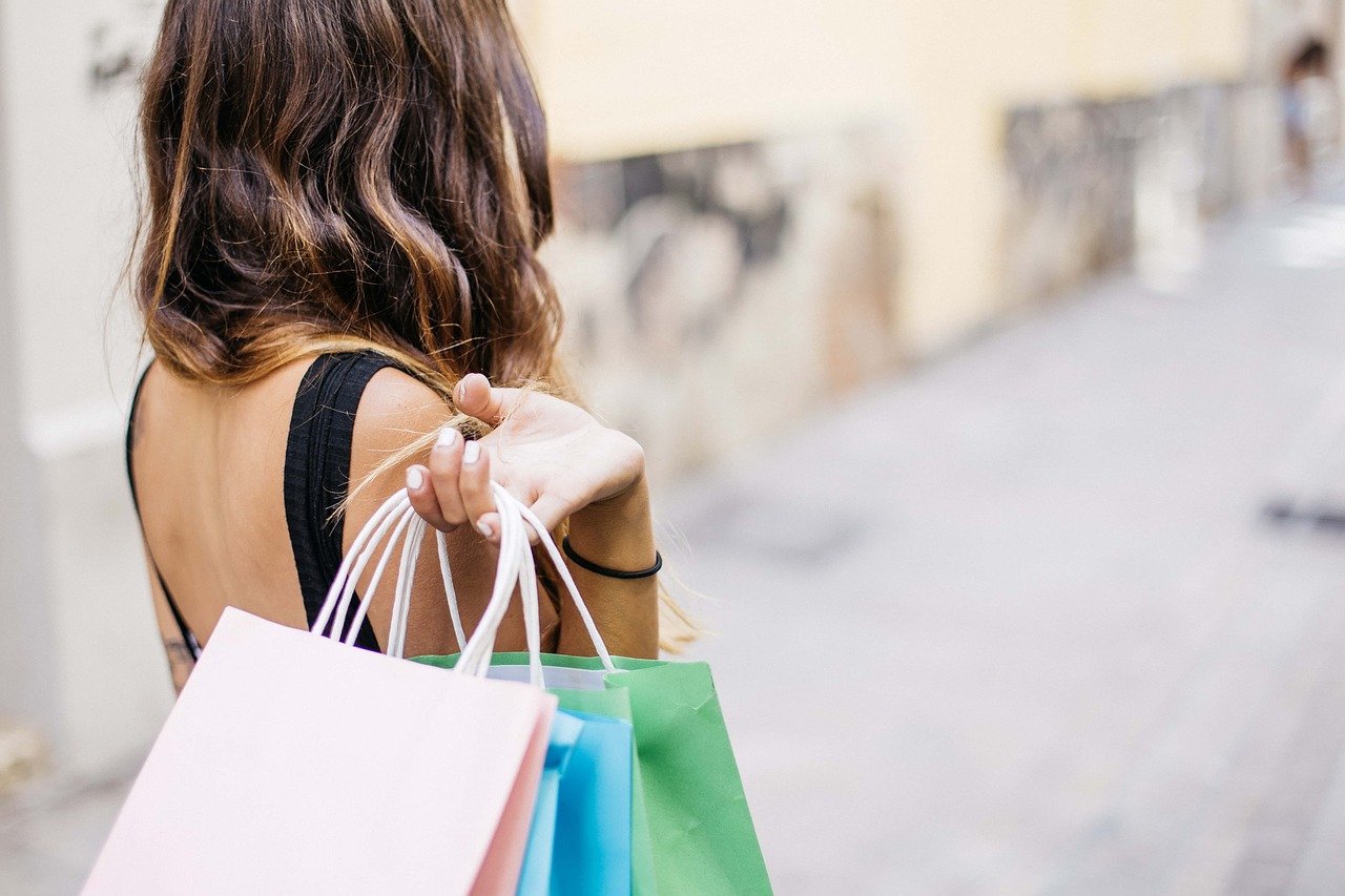 Femme sujette aux achats impulsifs sortant d'un magasin avec des nouveaux achats
